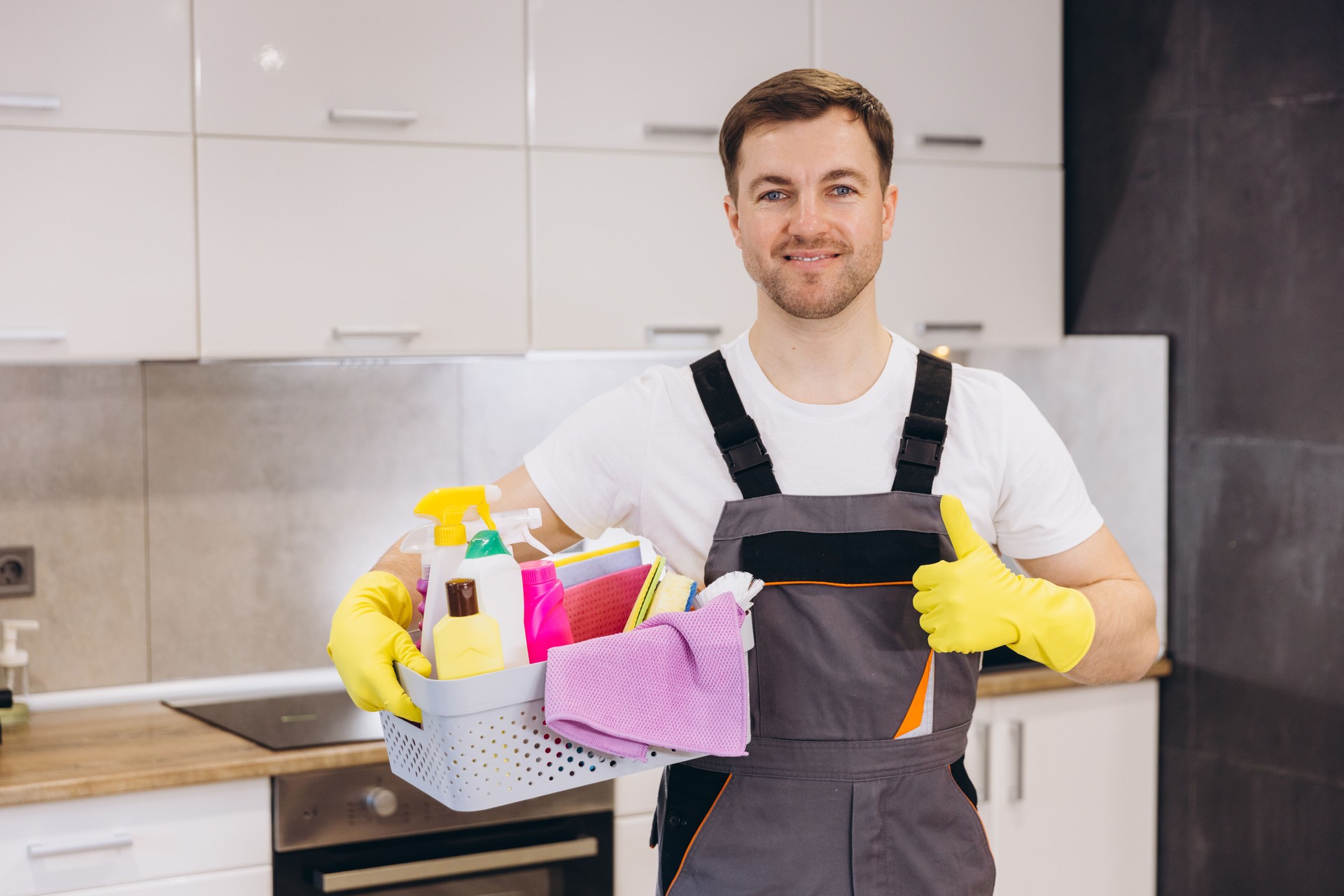 Cleaning company worker holding basket with cleaning products showing thumbs up